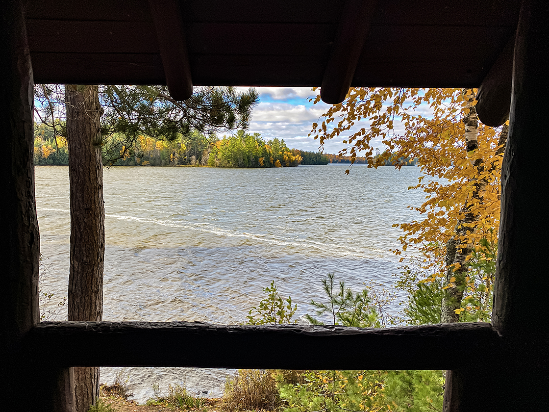 Tumultuous lake view framed by timbers of picnic shelter