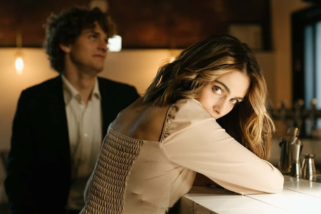 a girl sitting in a bar , who looking at a guy