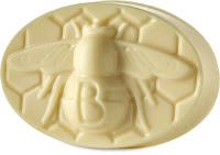 A oval  shaped yellow body balm with a 3D been coming out of it on a bright background
