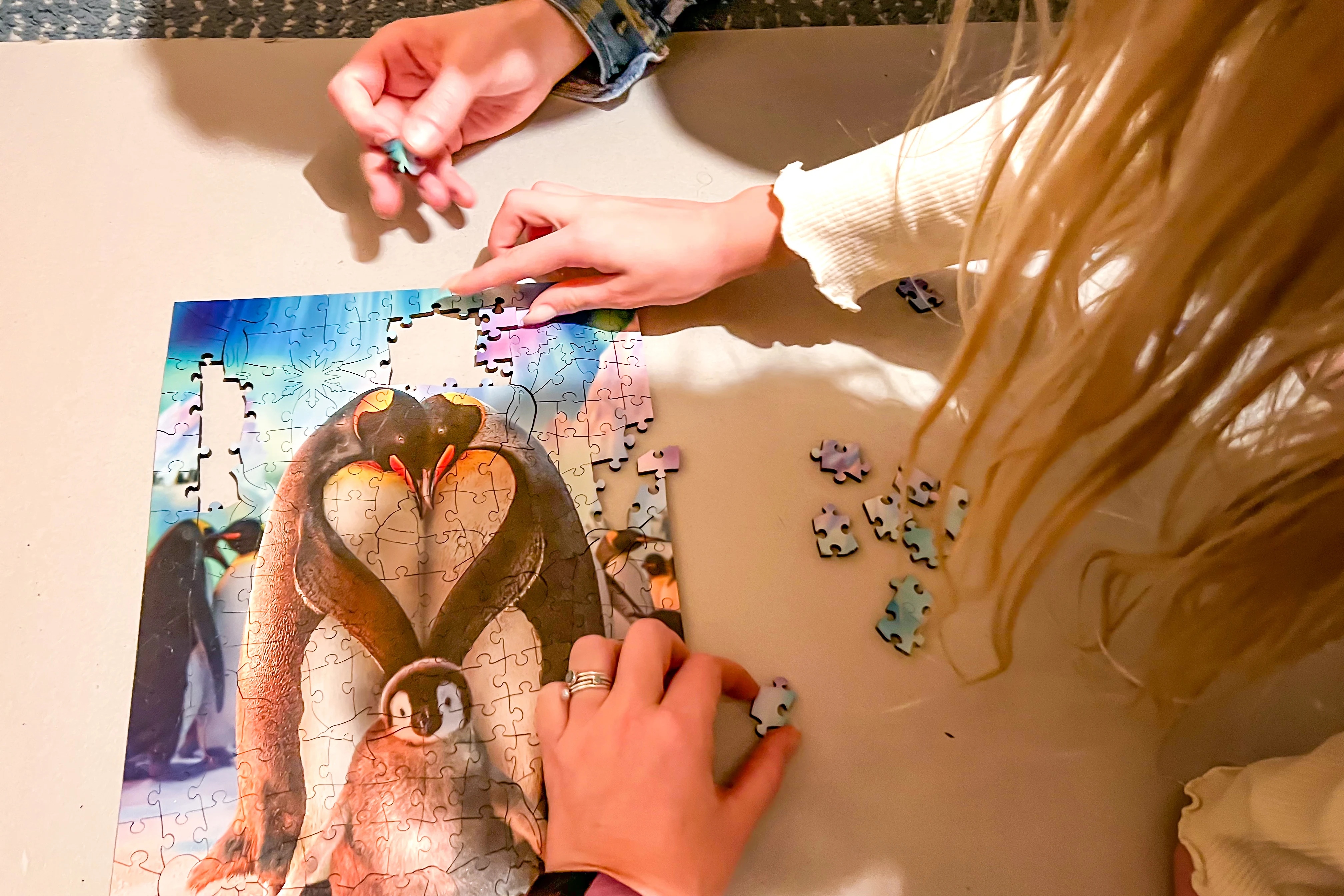 3 different hands completing a beautiful Christmas penguin jigsaw