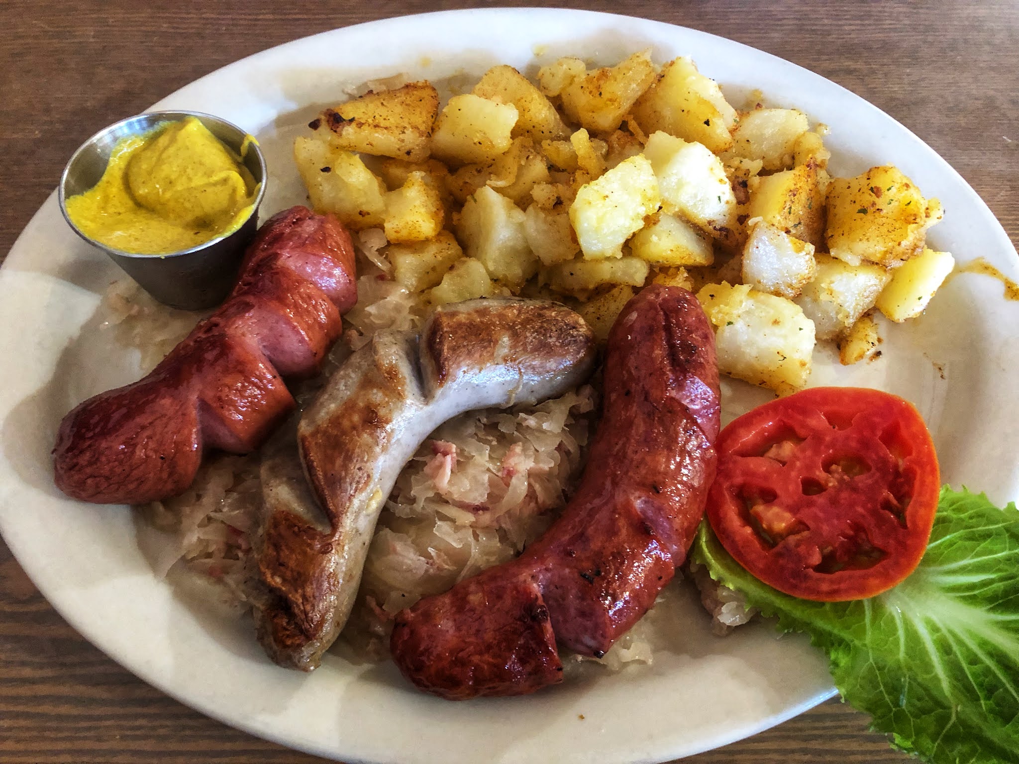 German sausage served with spicy mustard, potatoes, and bacon sauerkraut