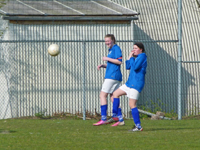 Twee vrouwen kijken verschrikt als er een voetbal op hen af komt