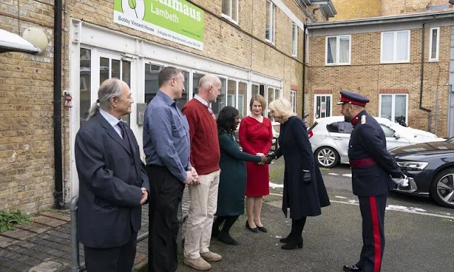 Queen Camilla wore a navy blue wool midi coat and black suede boots. The Queen visited the Emmaus boutique