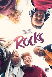 Six teenage girls looking down at the camera, smiling and posing. The text reads 'Rocks'.