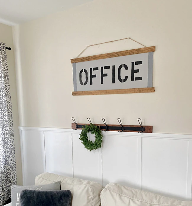office sign over sofa with hook rack and wreath