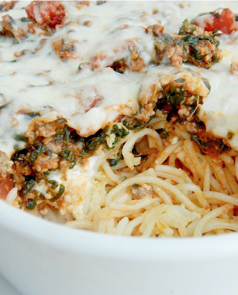 Up close look of baked florentine spaghetti in a white baking dish.