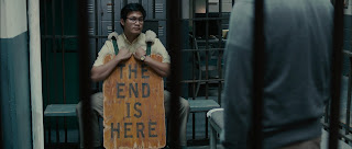 Fotograma de la película en prisión uno de los prisioneros lleva un cartel donde se lee "THE END IS HERE"