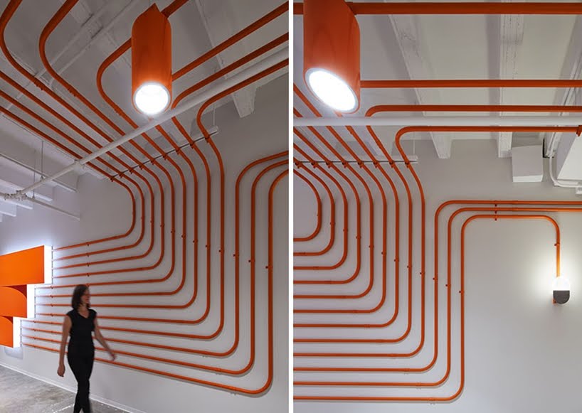 El diseño de esta oficina utiliza tubos de color naranja para guiar a las personas alrededor del espacio