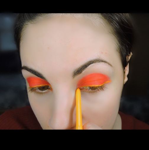 Ultima Beauty applying yellow gold eyeliner to upper lash line