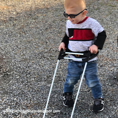 A toddler learning to walk with double white canes