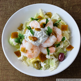 image of a bowl of Mediterranean shrimp salad with spiced Greek yogurt, served over lettuce with olives and feta