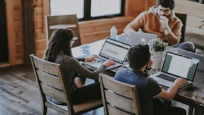 Three persons working in internet business work station with computers.