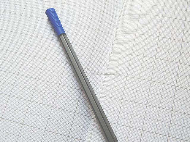 grid paper with blue and black pen on top