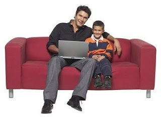 A father and child sitting on a sofa with a computer