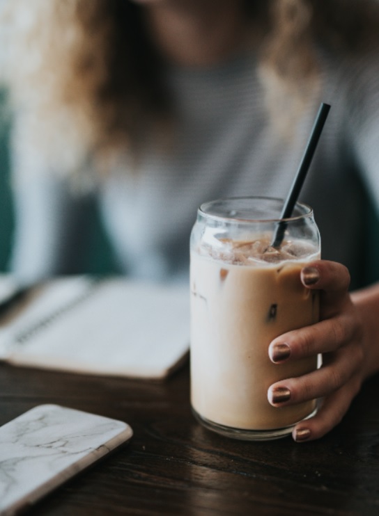 A lady is enjoying her fresh made oat milk in a mason jar.