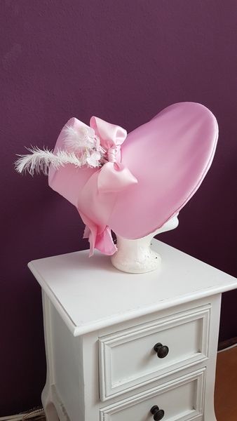 pink romantic era bonnet on a white nightstand