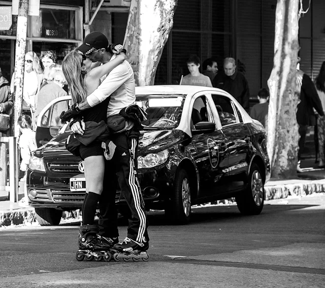 Una pareja de patinadores abrazados y besándose en la calle