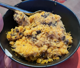 A small black bowl filled with a pale orange mush, with brown flecks. It looks frosty/icy like granita.