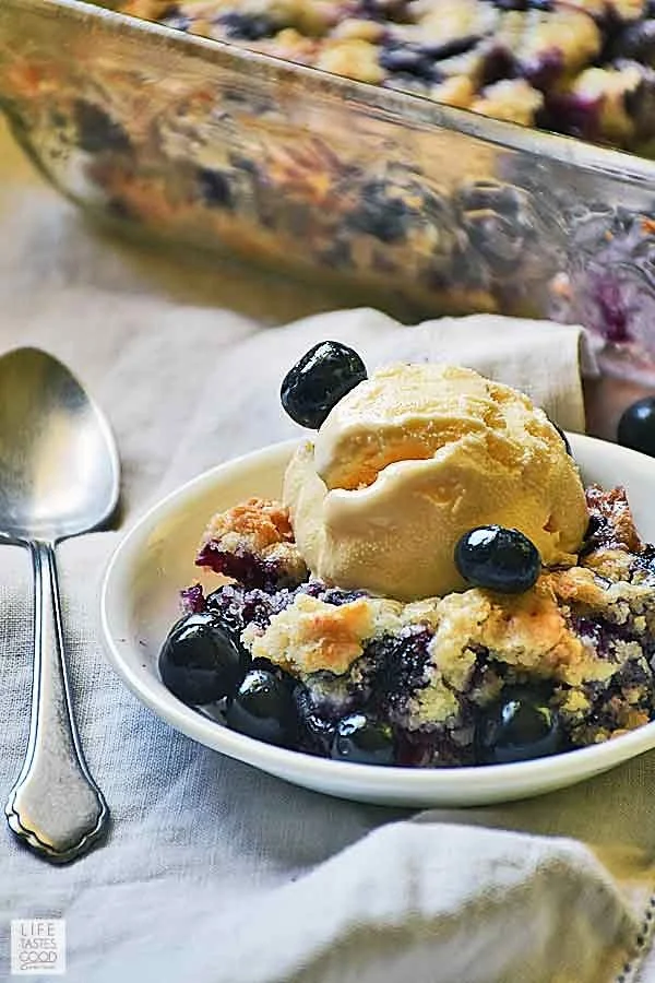 Blueberry Dump Cake with a scoop of vanilla ice cream in a white serving dish