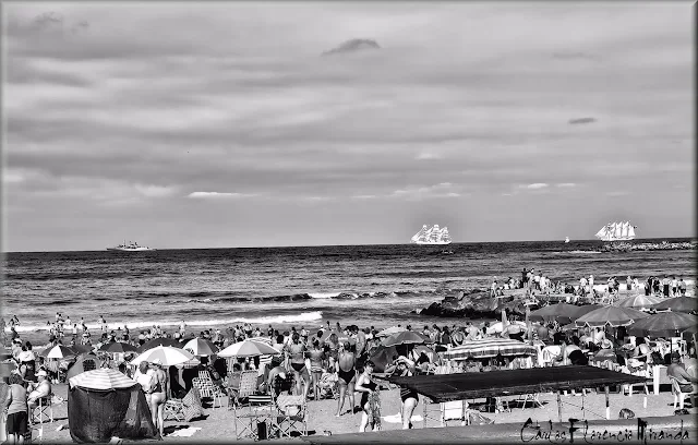 Blanco y negro.Gente en la playa y barcos en horizonte.