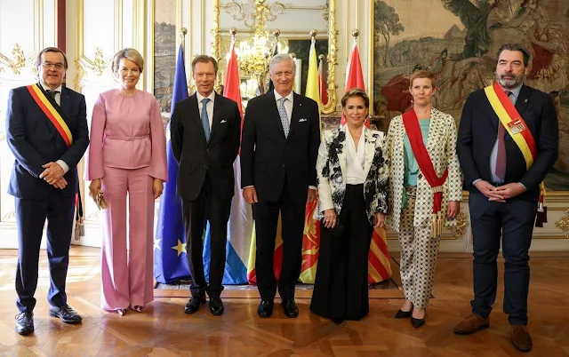 Duchess Maria Teresa wore a Chiaroscuro peak shoulder jacket by Alexander McQueen. Queen Mathilde wore a silk pink top by Natan