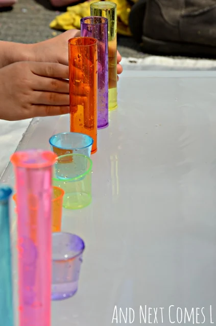 Close up of colorful cups filled with water as part of a fine motor activity for kids