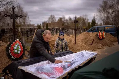 Vova, 10, olha para o corpo de sua mãe, Maryna, deitada em um caixão enquanto seu pai, Ivan Drahun, reza durante seu funeral em Bucha na semana passada