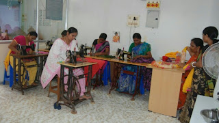 A group of women learning how to tailor from a teacher.