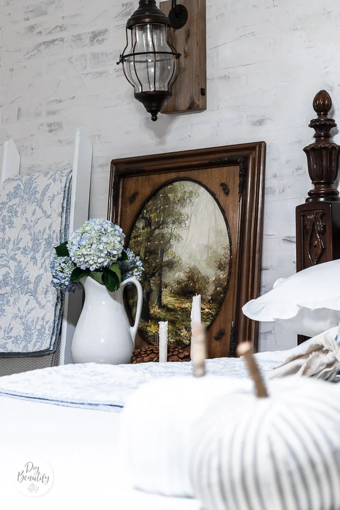 fall oil painting, blue hydrangeas in white ironstone pitcher, white and blue quilt hanging from blanket ladder