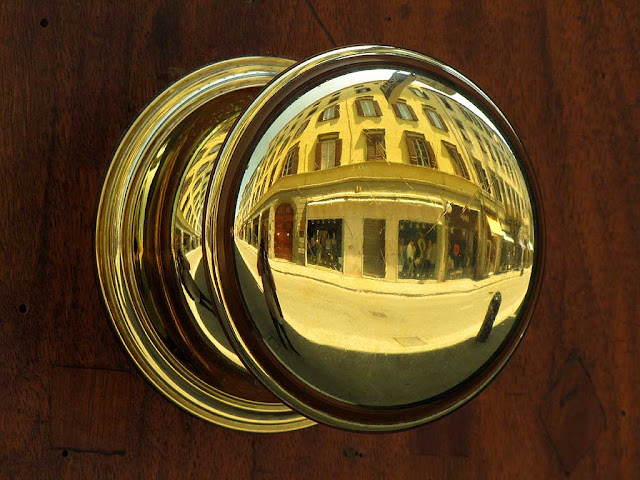 Via Ricasoli reflected in a polished brass door knob, Livorno