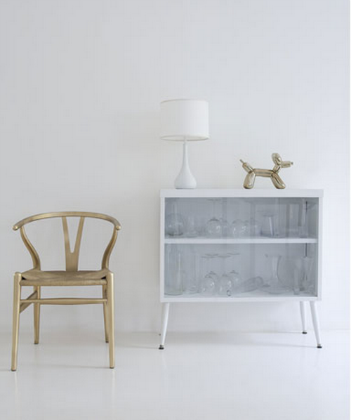 Zimmer mit weißer Wand und weißem Boden und einem gold lackierte Wishbone Chair