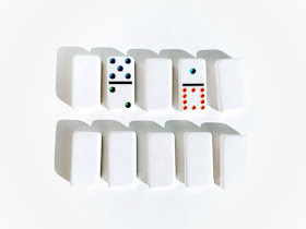 na zdjęciu dziesięć kamieni domino z czego osiem jest odwrócone tak,że nie widać oczek a dwa są odkryte i wskazują tą samą liczbę oczek jeśli przemnożymy przez siebie oczka z dwóch stron domino