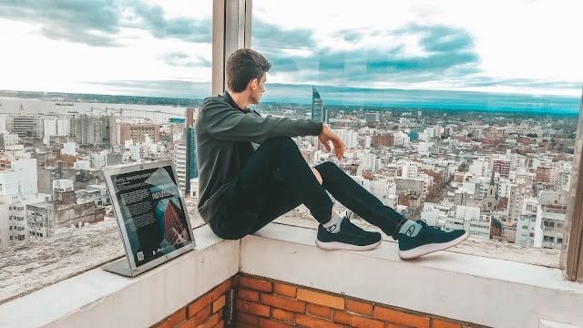 Menino sentado no muro, olhando para a cidade