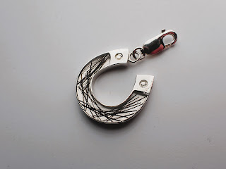 A bracelet charm in the shape of a horseshoe containing horse hair