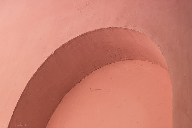 A Minimalist Photo of a Pink Curve on a Pink wall.