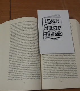 Das Bild zeigt ein aufgeschlagenes Buch mit dem Lesezeichen drin