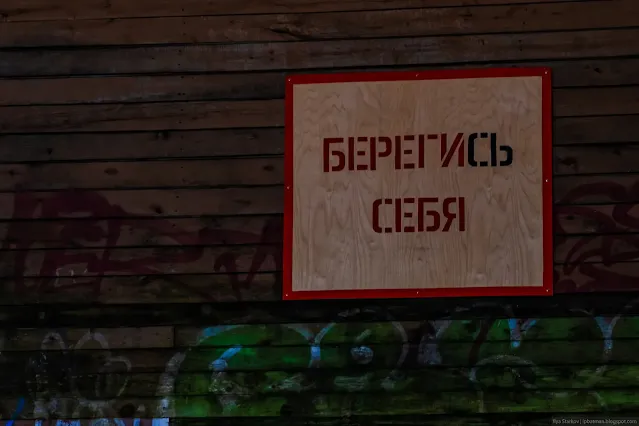 Табличка на стене деревянного дома Берегись себя