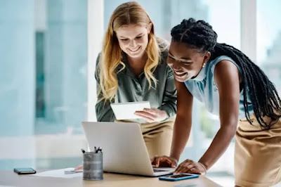 Two ladies standing with laptop on the table