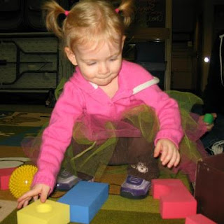 a toddler is playing with colorful blocks, balls, and scarves