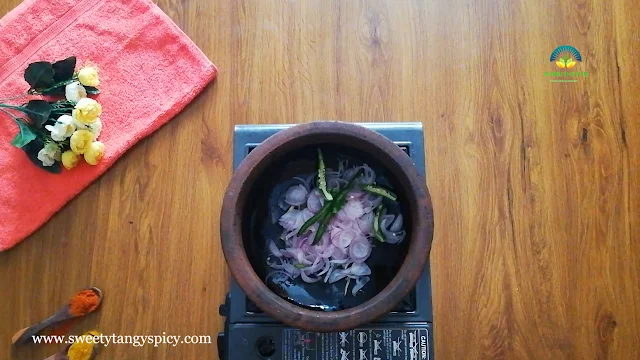 Adding Fragrant Curry Leaves to sautéed onions, green chilies, and ginger in a wide-mouthed earthen pot.