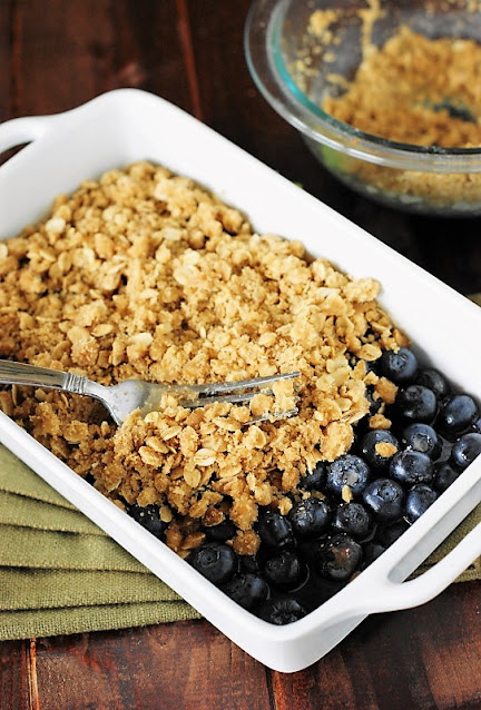 Layering Topping on Blueberries in Pan to Make Blueberry Crisp Image