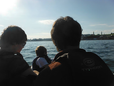 3 children sillhouetted in small boat on water