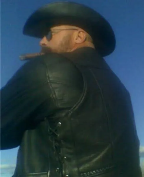 Big Daddy leather bear wearing black leather jacket from the rear for the cowboy hat on sunglasses smoking a cigar