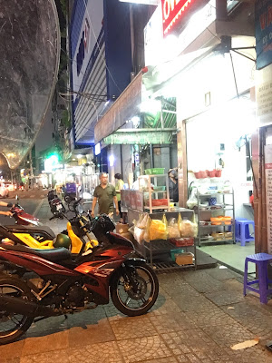 Street life outside a popular chicken noodle place.