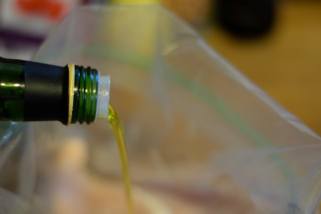 Extra Virgin Olive Oil being added to a resealable bag with the chicken in it.