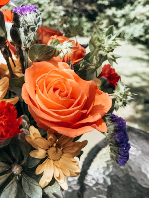 a beautiful orange rose surrounded by other flowers in a bouquet