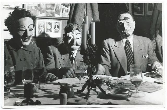 Drei maskierte Herren an einer Tafel