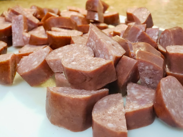 Cut up caribou sausage on white cutting board