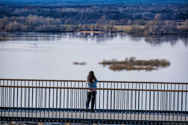 Девушка фотографируем с моста реку