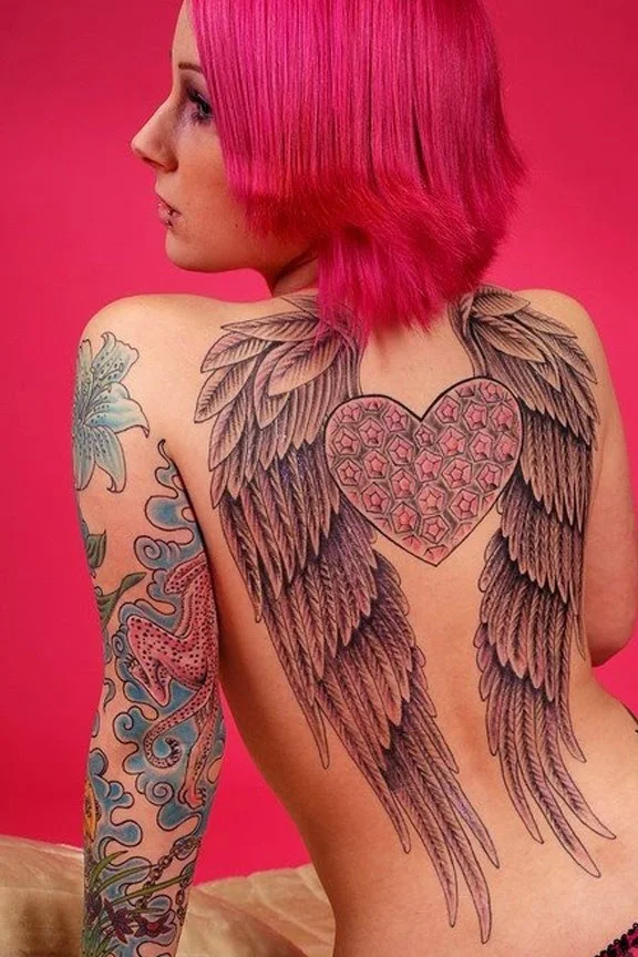 chicade espaldas con el pelo rosa, vemos tatuaje de dos alas que ocupan su espalda